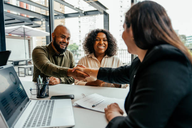 A woman meeting with a couple and shaking hands with the man.
