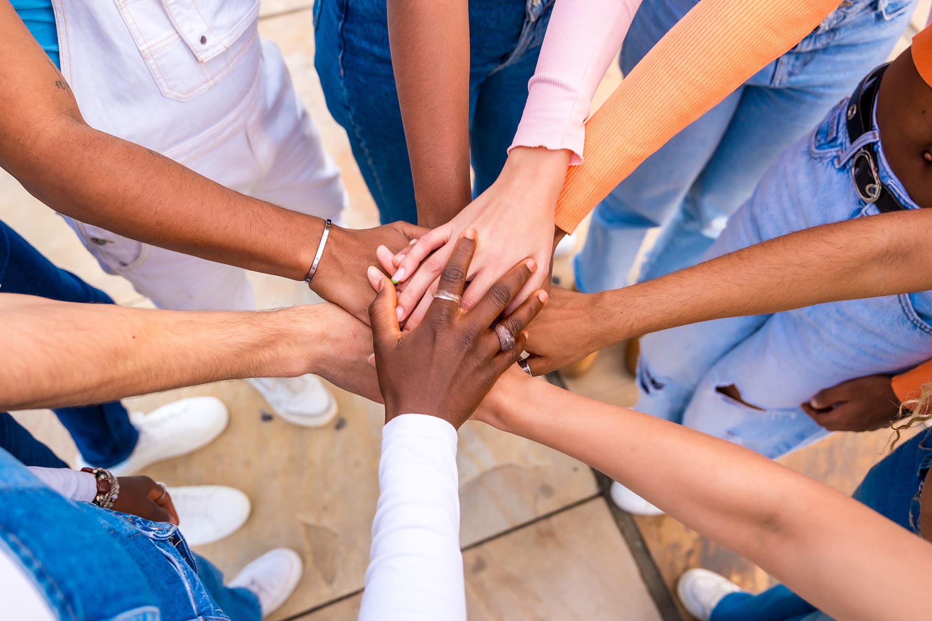 A diverse group of people place their hands together in unity. The image symbolizes collaboration, solidarity, and community strength.